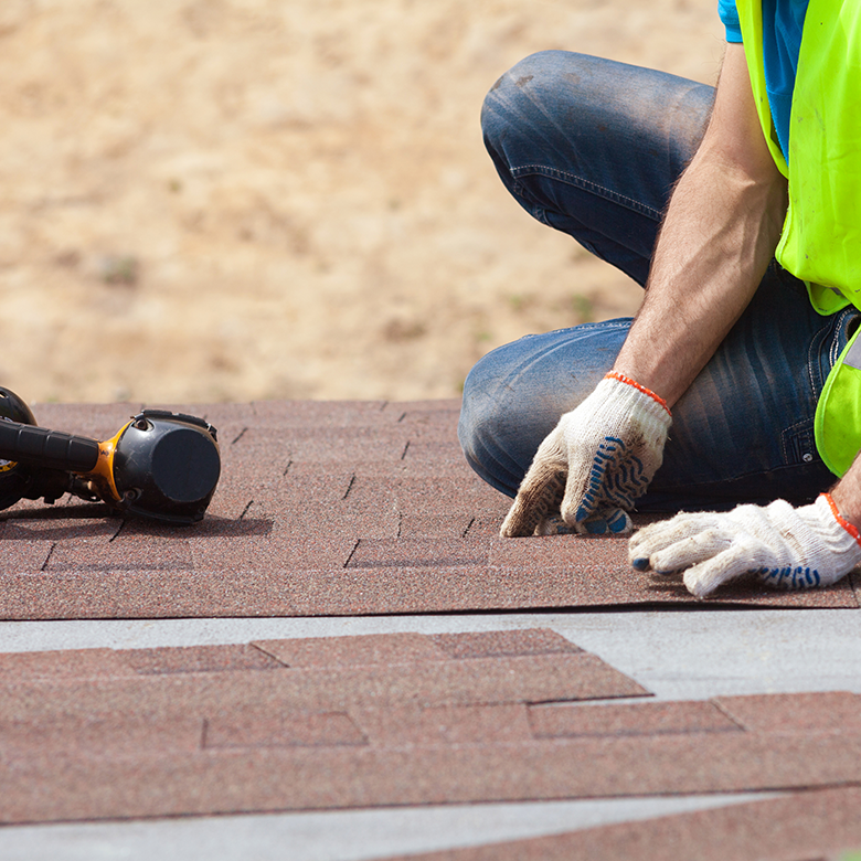 Roofer installing shingles rooftop