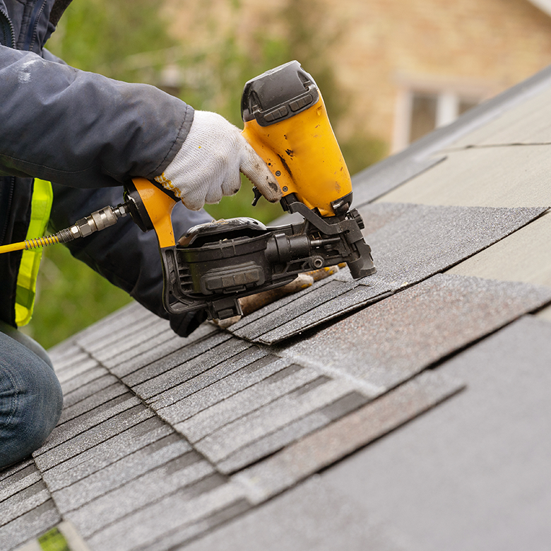 Worker installing asphalt roof shingles