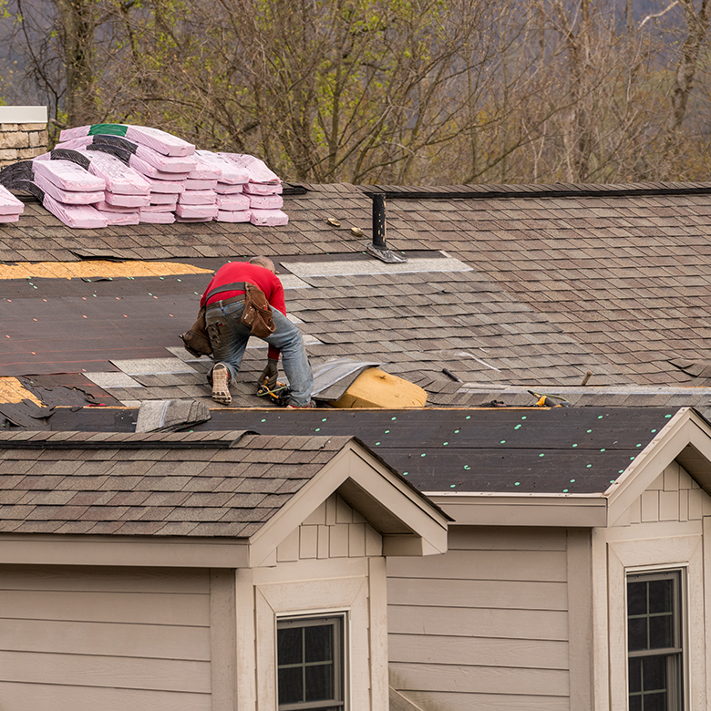 Roofer installing shingles on rooftop